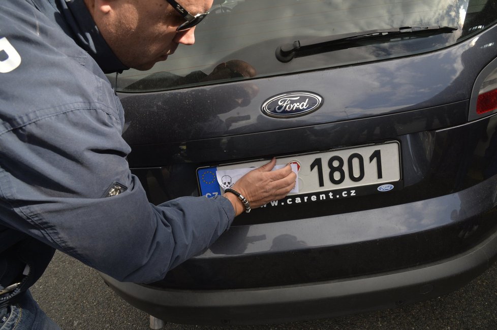 Taxikáře na letišti v Praze krotí policisté. Na vozy řidičů Uberu letí samolepky s nápisem Ilegal Transport.