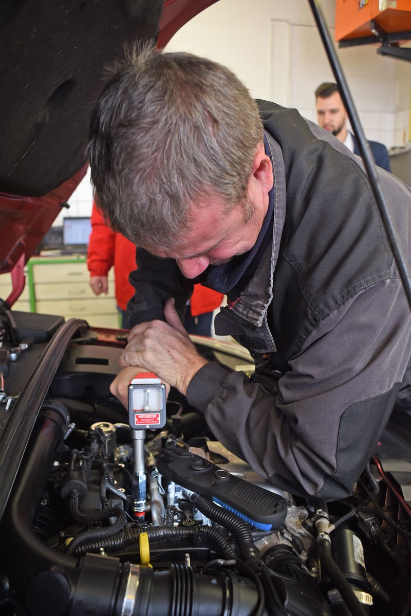 K měření kompresního tlaku válců se používá barometr se záznamem. Jeden mechanik drží zapnutý startér, druhý měřák v otvoru svíčky. Jak vidíte, je to chlapská práce pro obě ruce.