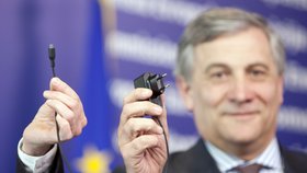 Viceprezident EU pro průmysl Antonio Tajani na tiskové konferenci předvádí nabíječku mobilních telefonů se standardizovaným konektorem.