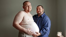 Těhotný táta a jeho manžel, který láskyplně hladí těhotenské bříško.