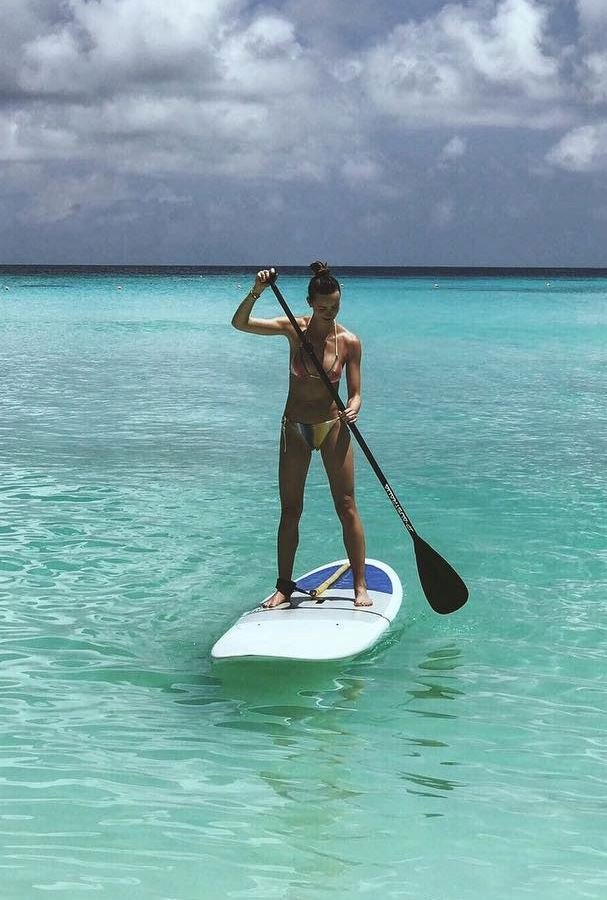 Ester na Maledivách cvičí na paddleboardu.