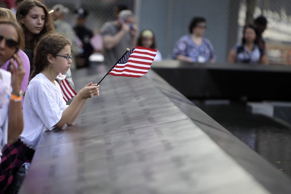 Dívka drží americkou vlajku u jména svého strýce na památníku obětem
