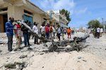 Civilisté stojí u vraku auta, které explodovalo poté, co na něj policie začala střílet. Stalo se tak v somálské metropoli Mogadišu, nedaleko prezidentského paláce. (14. 7. 2018)