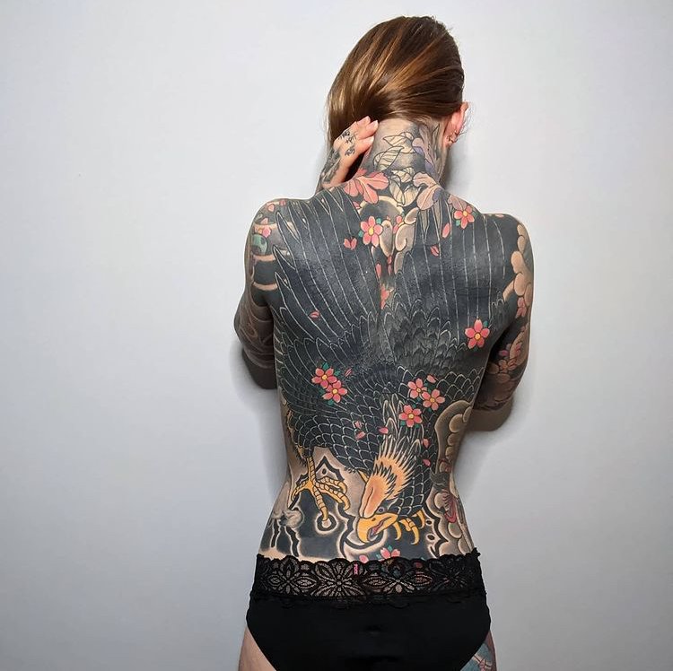 Proces tetování na zádech pokérované krásky.