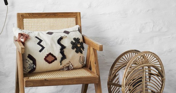 Boho styl koberce a polštářku s geometrickými ornamenty v různých barvách, které k sobě vzájemně ladí.