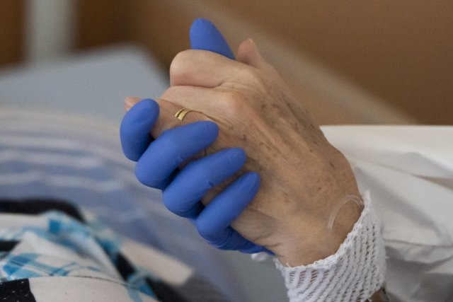 Kaplanka Doubravka Vokáčová drží za ruku pacientku s covidem-19 6. listopadu 2020 na Oddělení geriatrie a následné péče pražské Thomayerovy nemocnice.
