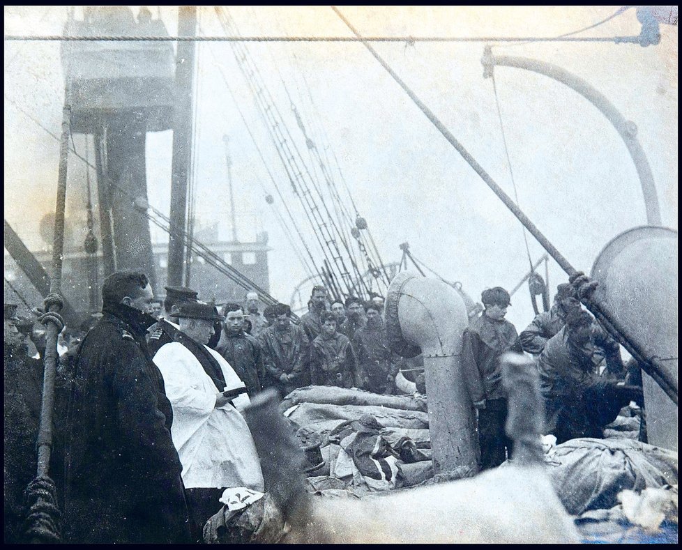 Pozůstalí se loučí s oběťmi největšího lodního neštěstí v historii. Zatímco kněz odříká modlitby, námořníci shazují těla do moře.