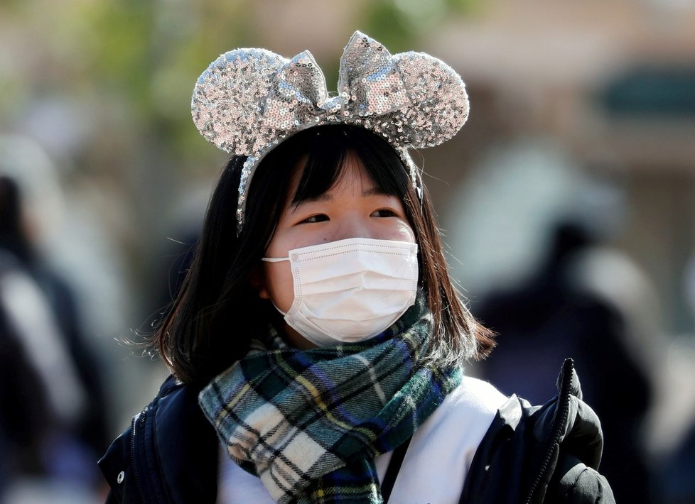 Návštěvníci tokijského Disneylandu stojící v rouškách před zábavním parkem