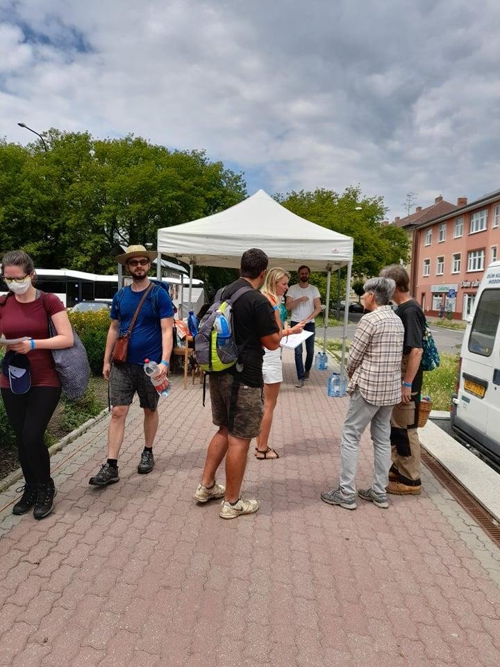 Shromaždiště Hodonín, před kulturním domem. Dobrovolníci nafasují pásku, pití, kšiltovku a autobusy je pak odvezou na místo práce (3. 7. 2021)