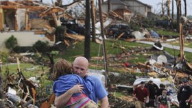 Muž nese v náručí holčičku, kterou vyprostili z trosek domu, který zcela zničlo tornádo