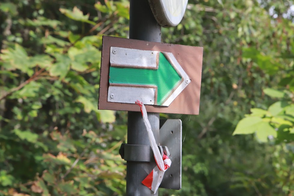 Na přecházení rušné silnice směřuje chodce a cyklisty zelená turistická značka.