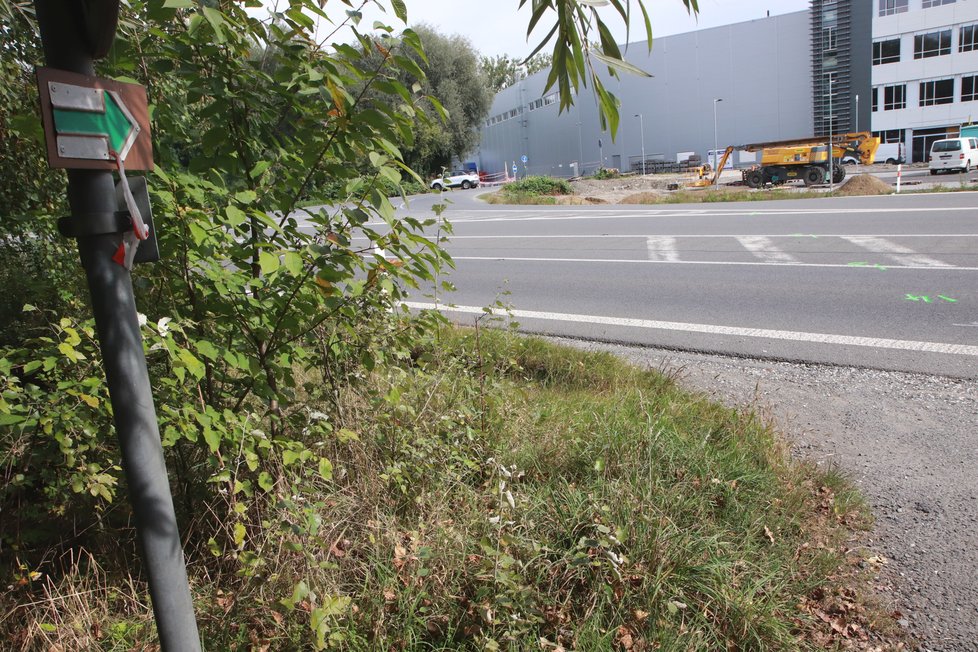 Na přecházení rušné silnice směřuje chodce a cyklisty zelená turistická značka.