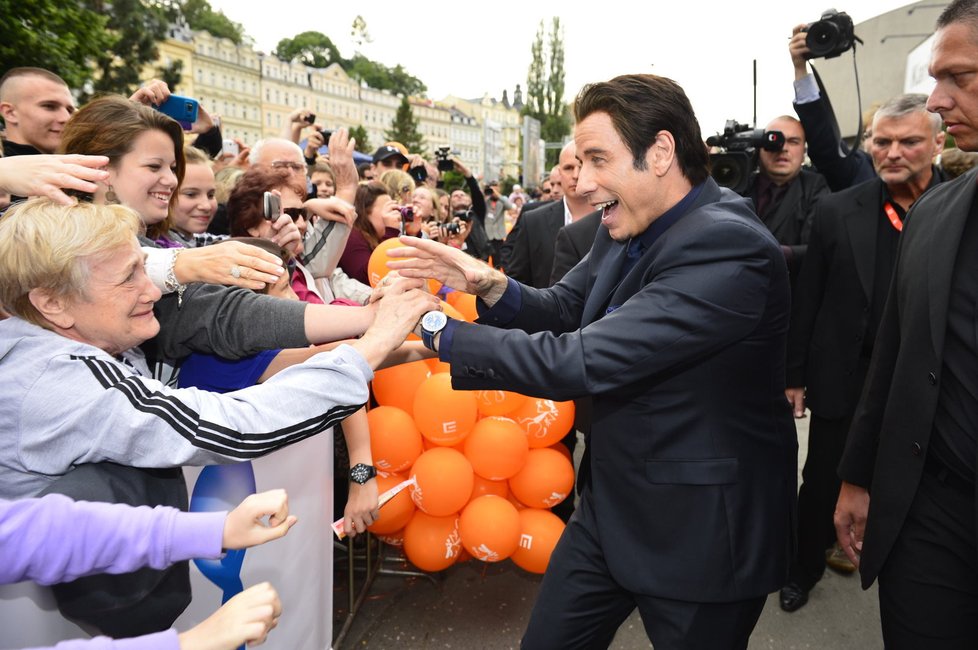 Diváci festivalu šílí, John Travolta se zdraví s fanoušky.