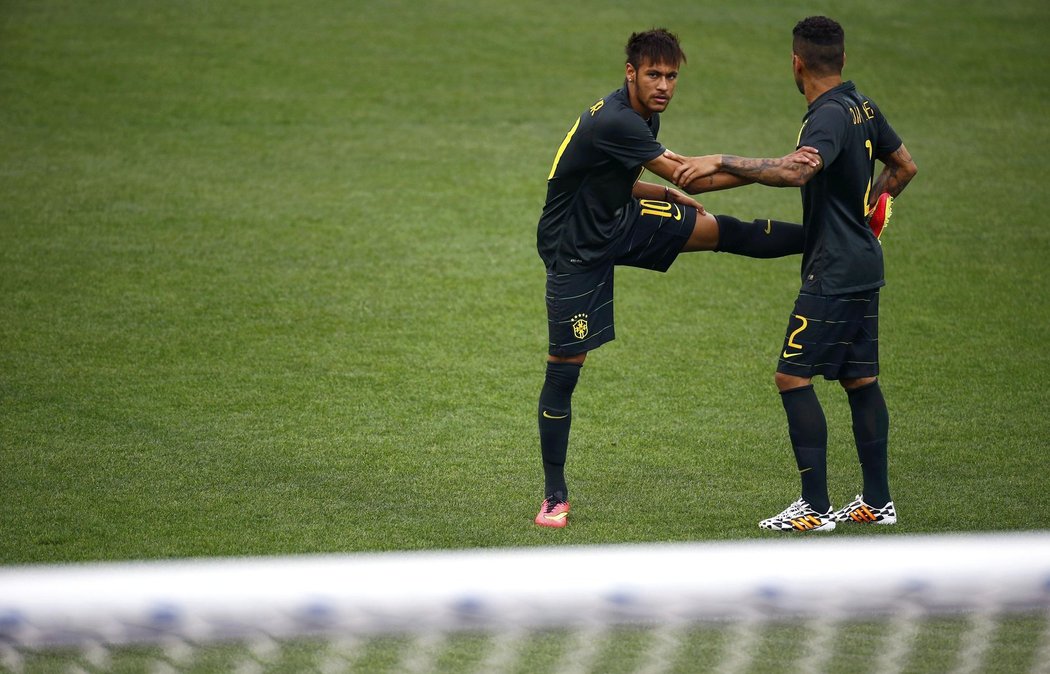 Brazilský útočník Neymar se protahuje se spoluhráem.