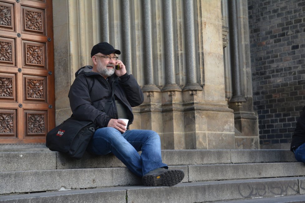 Lidé posedávají na schodech u kostela