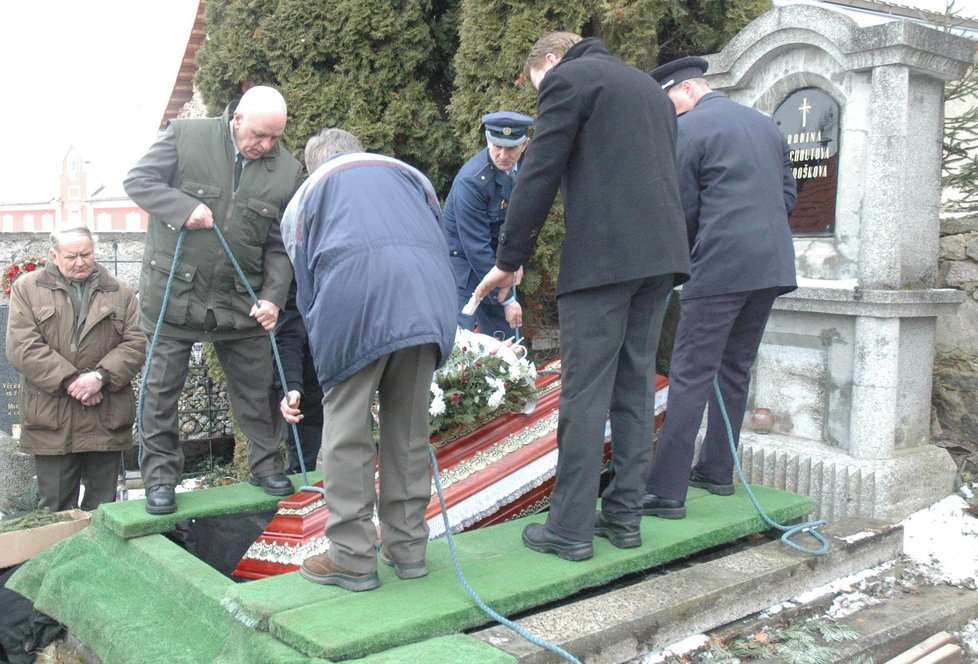 Rakev je spouštěna do rodinné hrobky.