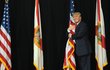 Republikánský kandidát na prezidenta Donald Trump obejímá americkou vlajku při vstupu na pódiu. Chystá se promluvit v amfiteátru MidFlorida Credit Union v Tampě na Floridě, třetím z pěti měst, které Trump navštěvuje.