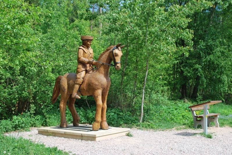 Dřevěné sochy lemují stezku K. J. Erbena. Z lesa na koni vyjíždí švarný dřevěný Pán – kdo jiný než hrdina básně Zlatý kolovrat.