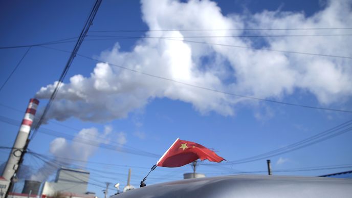 Čínská vlajka na střeše automobilu projíždějícího kolem uhelné elektrárny ve městě Charbin v provincii Chej-lung-ťiang.