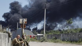 Vojáci hlídají hořící zásobníky s ropou.
