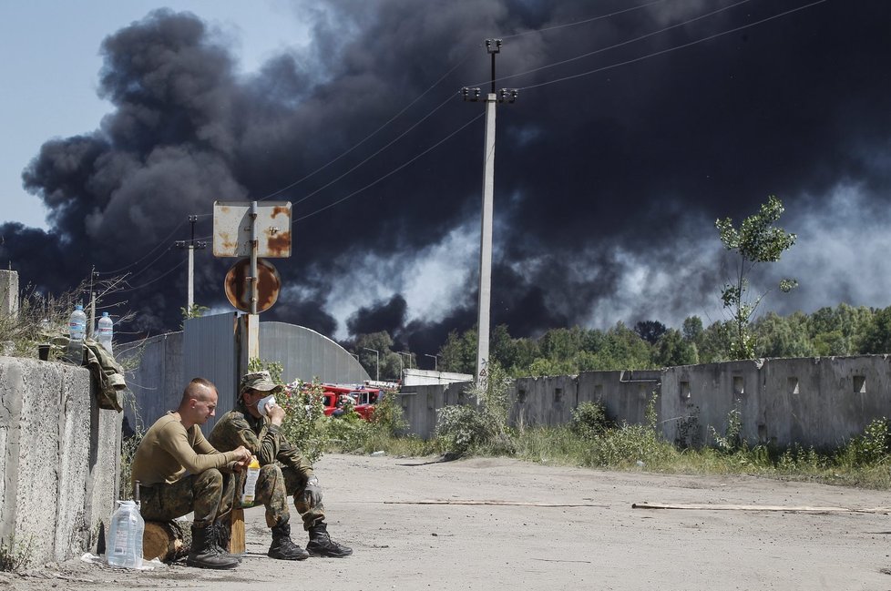 Vojáci hlídají hořící zásobníky s ropou.