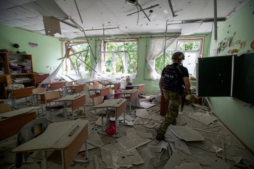 Policista obhlíží rozbombardovanou školu v Marince v Doněcké oblasti (31. 5. 2022).