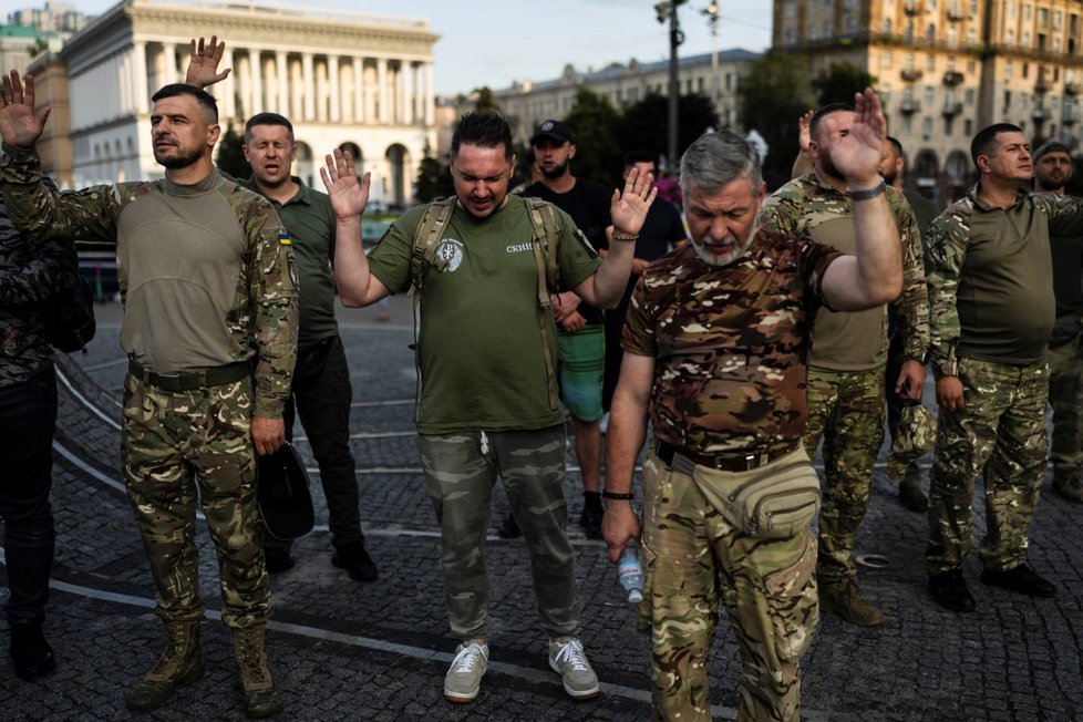 Civilisté a ukrajinští vojáci se modlí během bohoslužby v Kyjevě (14. 7. 2023)