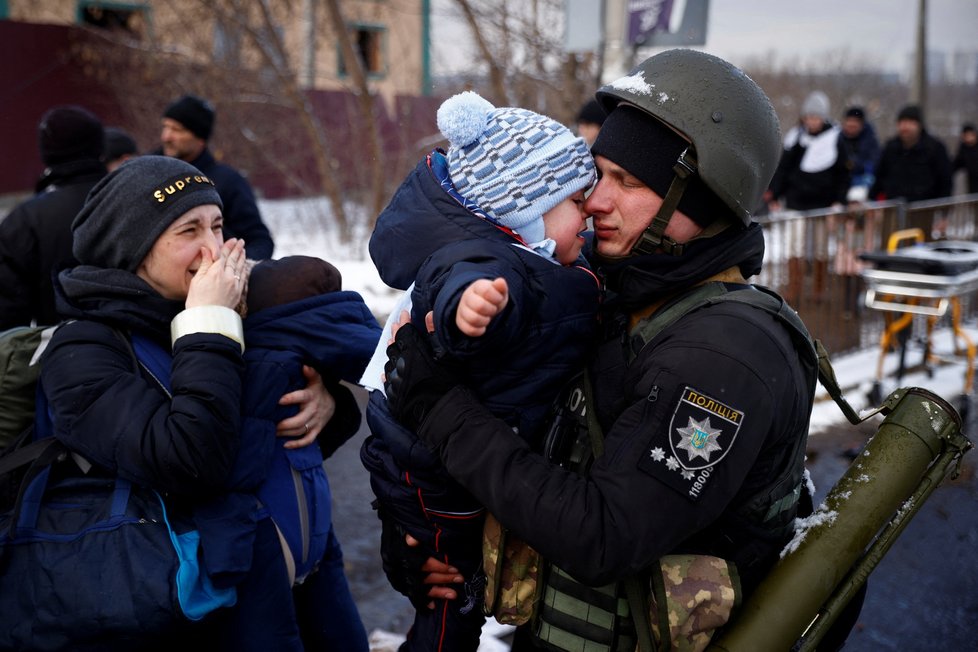 Pohled, který trhá srdce. Žena v slzách svírá miminko a sleduje manžela, policistu, který se před narukováním loučí s jejich synem.