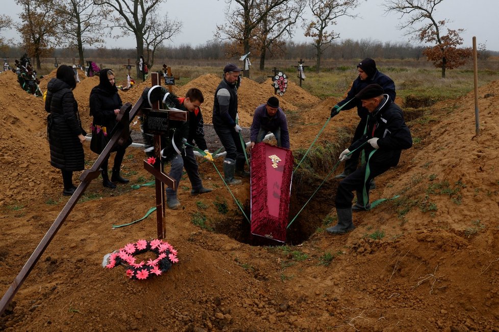 Funebráci ukládají do hrobu rakev s tělem místního obyvatele Artema, který zemřel během ruské okupace (Cherson, 17.11.2022)