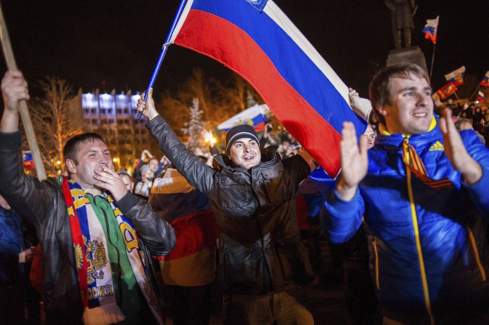 Lidé na náměstí v Sevastopolu jásají a mávají ruskými vlajkami.