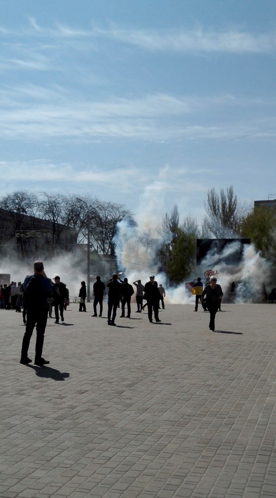 Lidé prchají před slzným plynem během protestu proti Rusům v Chersonu (27. 4. 2022)