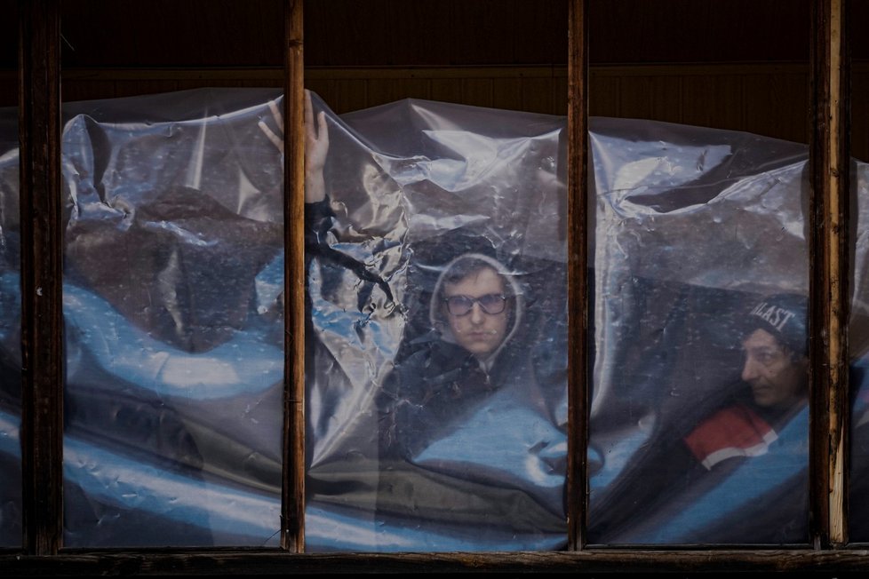 Ukrajinci se snaží zakrýt rozbitá okna během války s Ruskem.