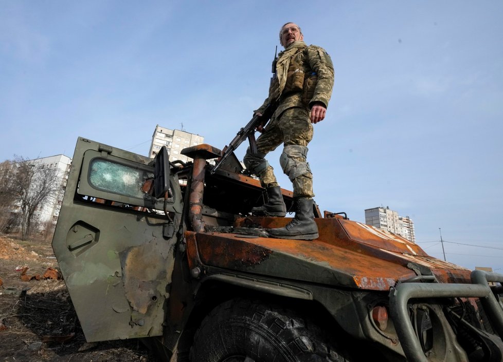 Válečná Ukrajina - Ukrajinský voják stojí na zničeném ruském obrněném transportéru po nedávné bitvě v ukrajinském Charkově.
