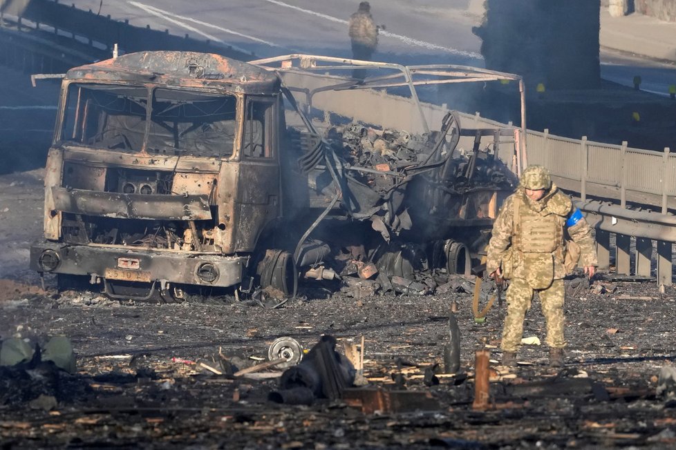 Ukrajinský voják před zničenou vojensku dodávkou v Kyjevě.