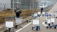Člověk prochází kolem vozíků se zavazadly na mezinárodním letišti Boryspil