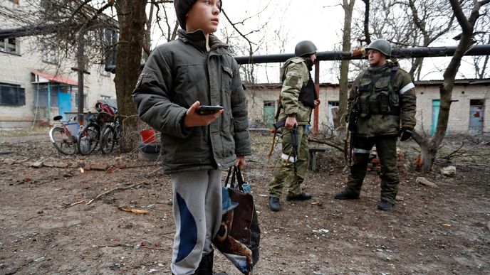Chlapec stojí před činžovním domem, který byl podle místních poškozen ostřelováním, v separatisty ovládaném městě Yasynuvata v Doněcké oblasti