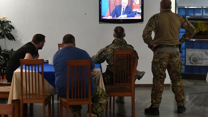 Vojáci na separatistickém území Ukrajiny sledují Putinův projev.