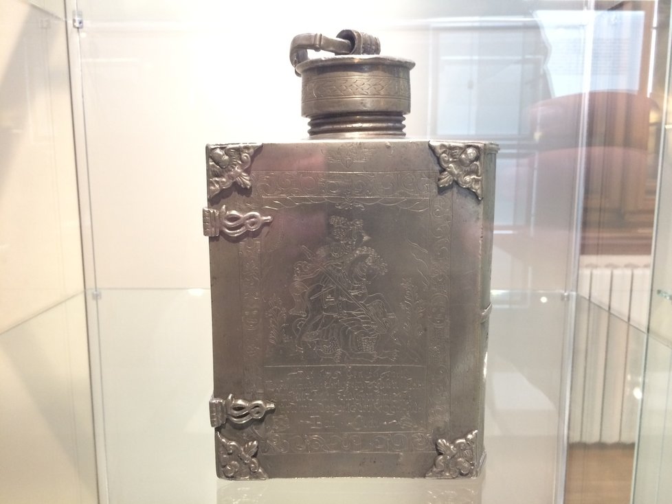 Na první pohled nápaditá kovová láhev ve tvaru knihy s rytinou sv. Jiří.