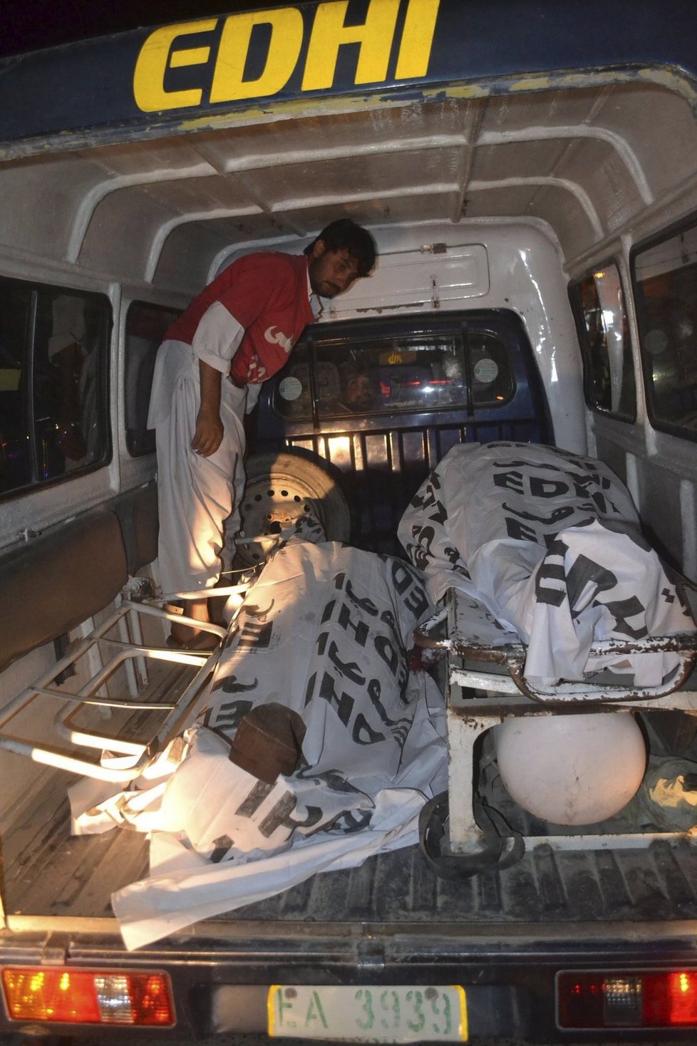 Ozbrojenci v Pákistánu přepadli autobus: Záchranář stojí nad těly dvou mrtvých obětí.