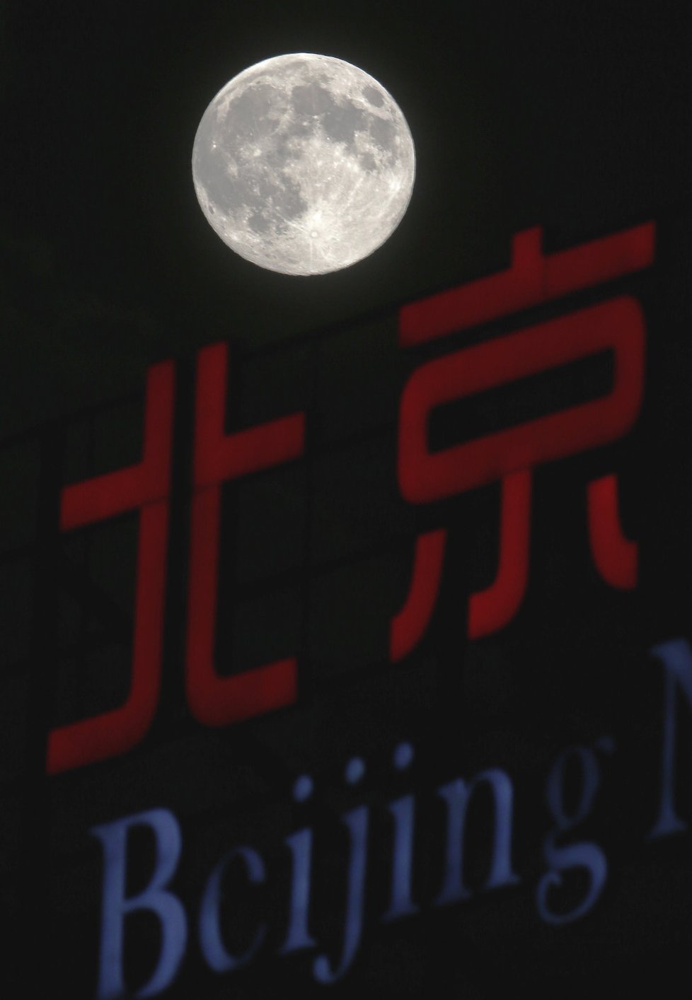 Měsíc osvěcuje nápis Peking v Číně.