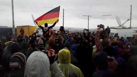 Uprchlíci v táboře Idomeni skandují s německou vlajkou.