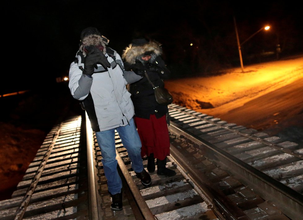 Uprchlíci přecházejí pěšky hranici z USA do Kanady.