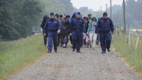 Policisté eskortují běžence do uprchlického tábora.