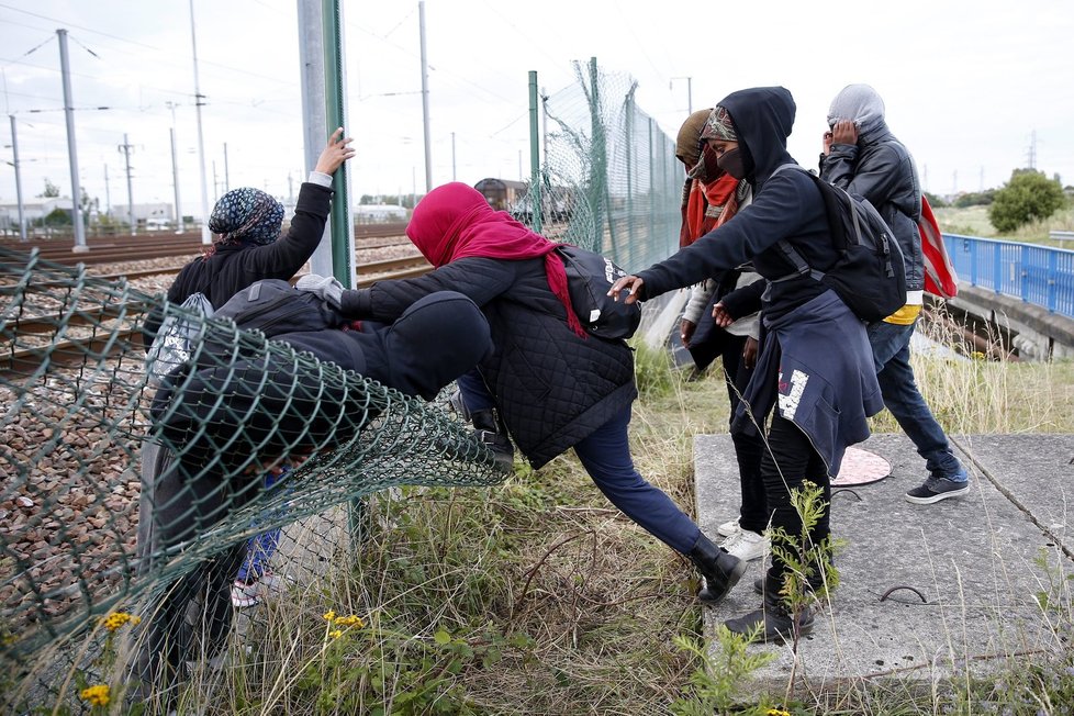 Uprchlíci přelézají plot a snaží se eurotunelem dostat do Velké Británie.