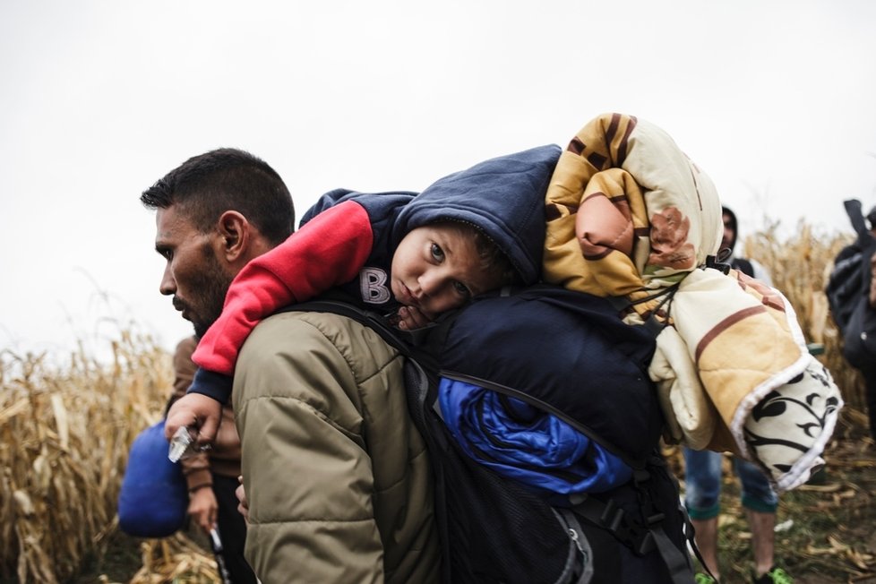 Uprchlík z Iráku kráčí se synem na zádech k přechodu Bapska na srbsko-chorvatské hranici.
