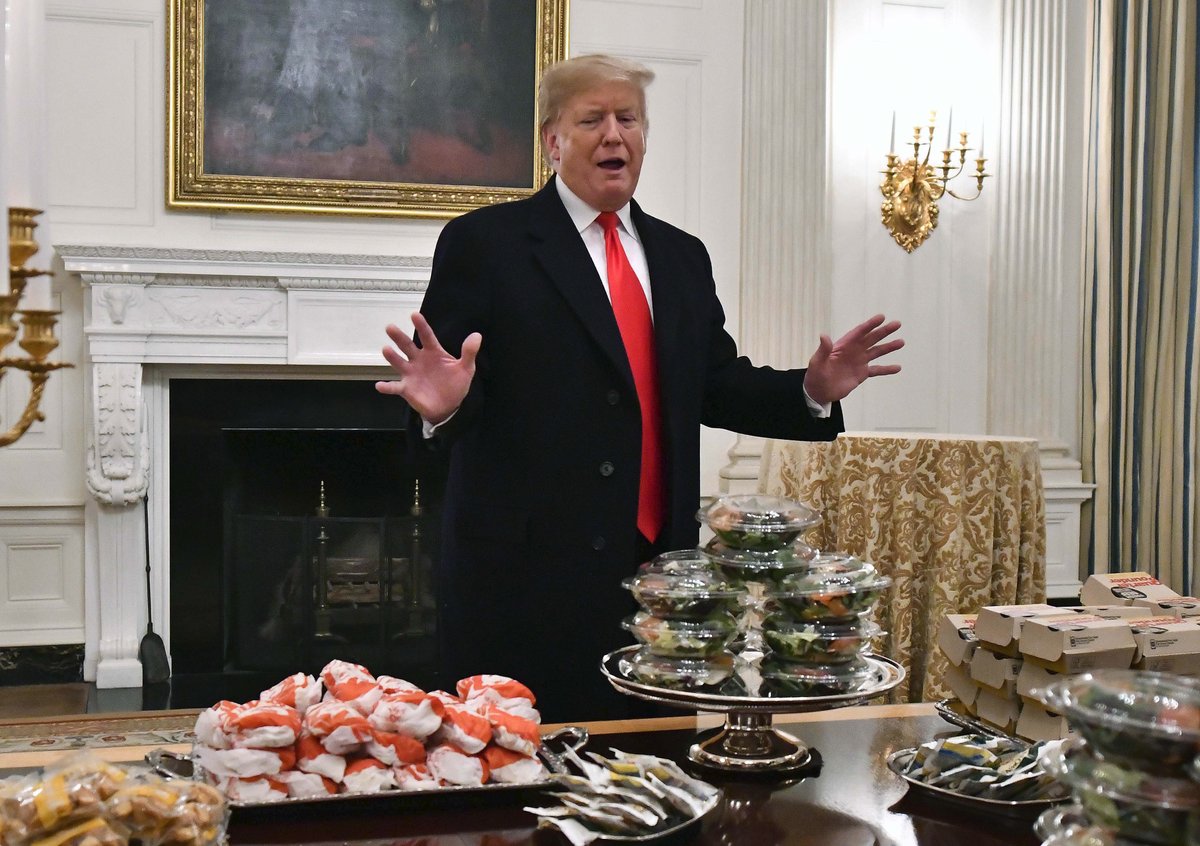 USA svírá rozpočtová krize. Prezident Trump musel za vlastní peníze uspořádat hostinu pro univerzitní sportovce, objednal jim pizzu a hamburgery z &#34;Mekáče&#34;.