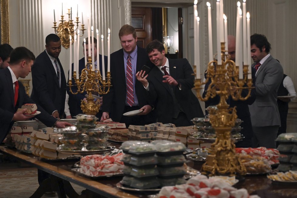 USA svírá rozpočtová krize. Prezident Trump musel za vlastní peníze uspořádat hostinu pro univerzitní sportovce, objednal jim pizzu a hamburgery z „Mekáče“.