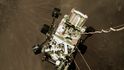 Záběr na rover NASA Perseverance klesající s padákem k povrchu Marsu.