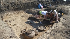 Archeologové čistí jeden z nalezených pravěkých hrobů. Byla v něm i zachovaná keramika.