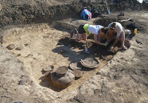 Archeologové čistí jeden z nalezených pravěkých hrobů. Byla v něm i zachovaná keramika.
